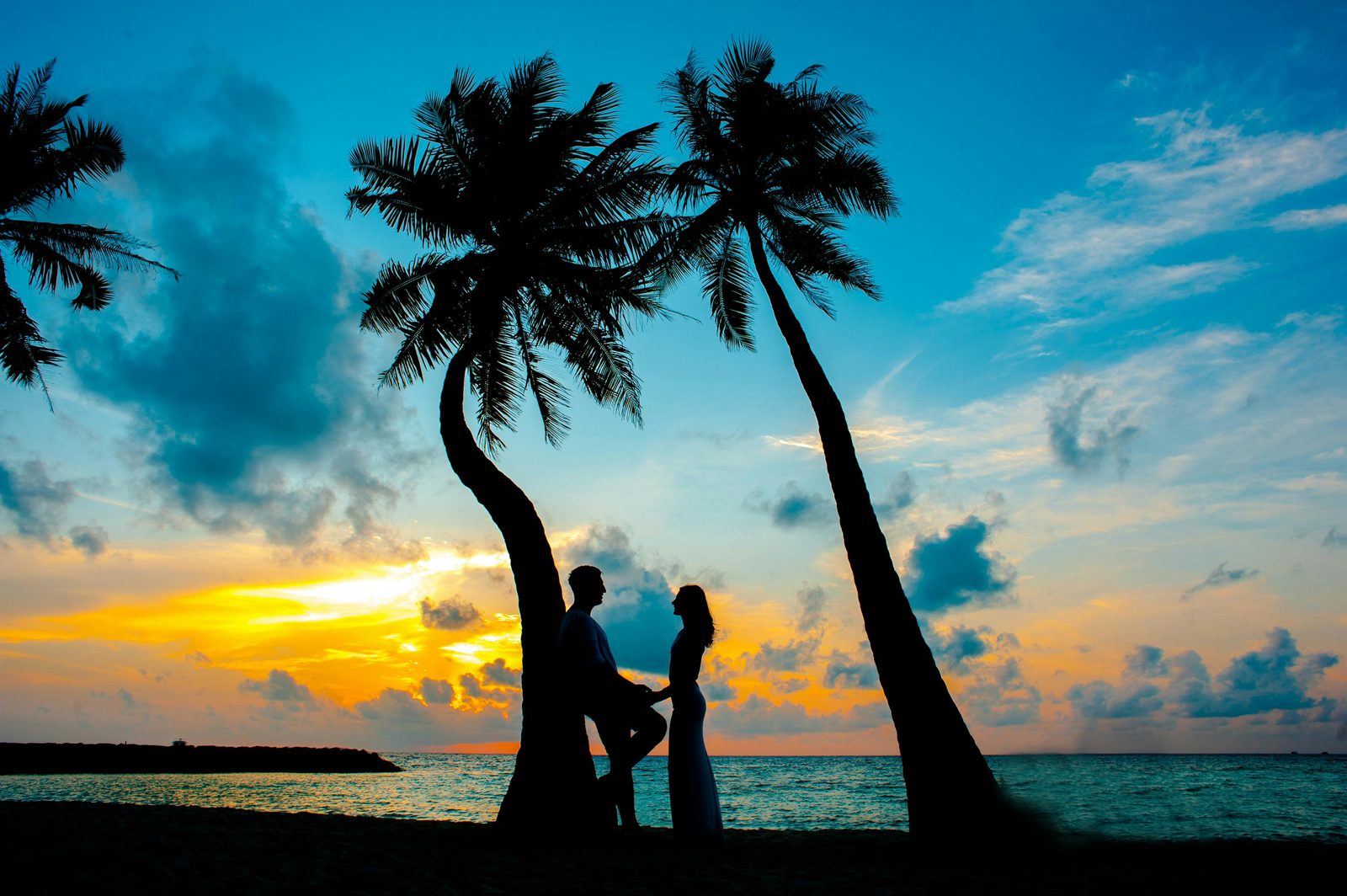 Couple silhouette devant un coucher de soleil sur la plage — voyage de noces